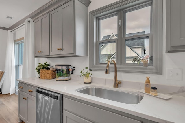 kitchen featuring a sink, gray cabinets, stainless steel dishwasher, and light wood-style flooring