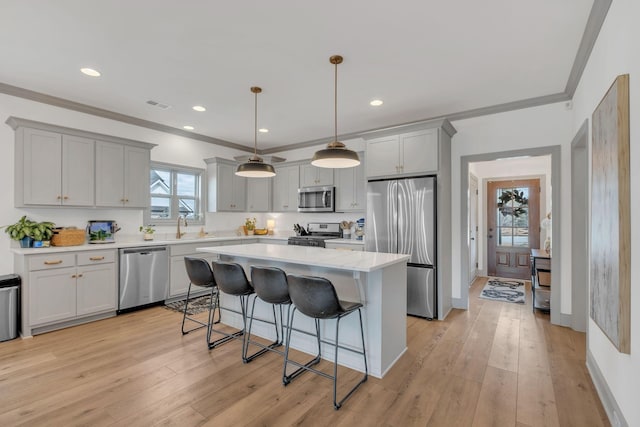 kitchen with appliances with stainless steel finishes, a breakfast bar, light wood-style floors, gray cabinets, and visible vents