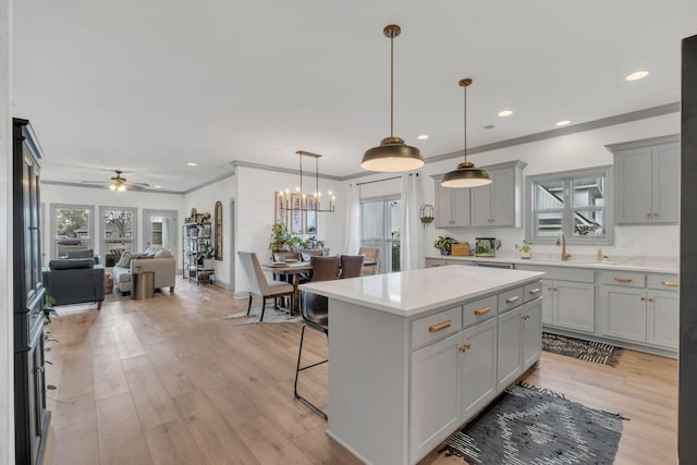 kitchen with open floor plan, gray cabinetry, ornamental molding, and a center island
