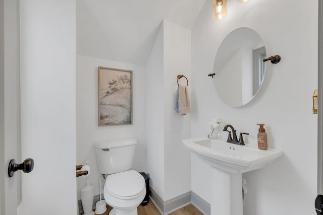 half bathroom with a sink, baseboards, toilet, and wood finished floors