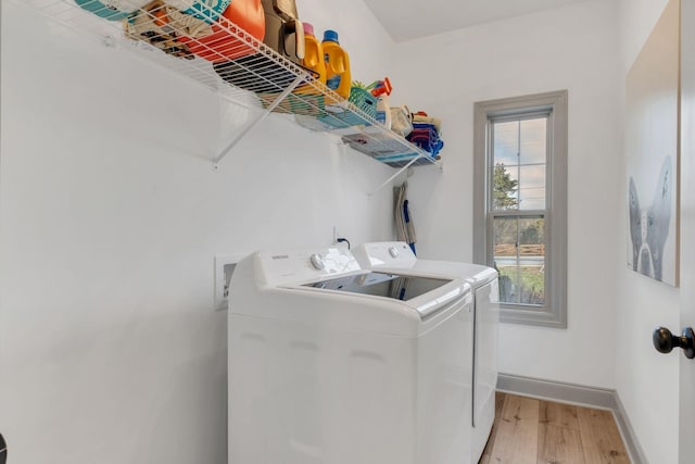 washroom with independent washer and dryer, laundry area, baseboards, and light wood finished floors