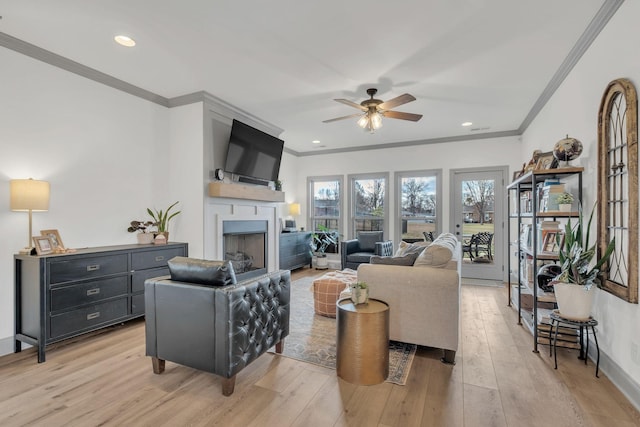 living area featuring a ceiling fan, a fireplace, light wood-style floors, ornamental molding, and recessed lighting