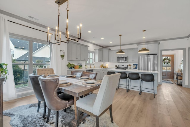 dining space with crown molding, a chandelier, light wood-style flooring, and visible vents