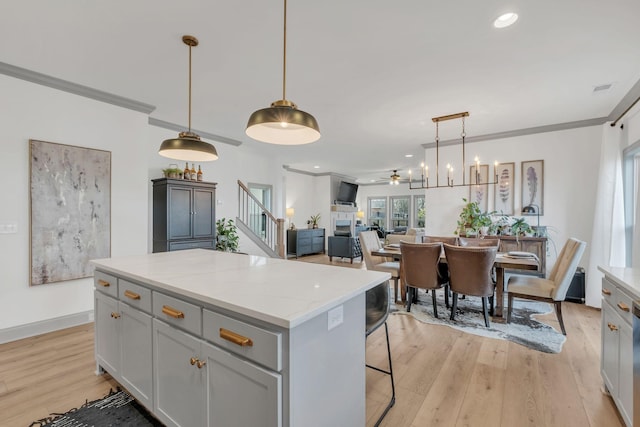 kitchen featuring a kitchen island, hanging light fixtures, ornamental molding, and light wood-style floors