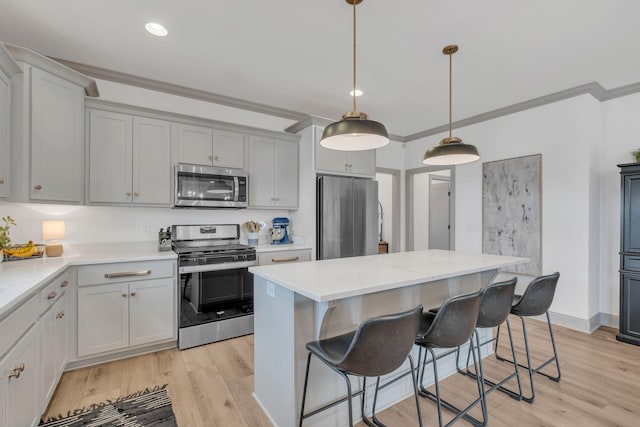 kitchen featuring crown molding, stainless steel appliances, a kitchen island, and light countertops