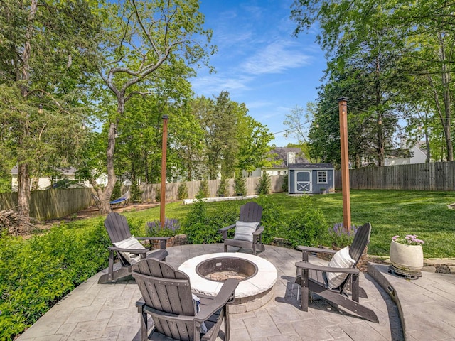 view of patio featuring an outdoor structure, a fire pit, a shed, and a fenced backyard
