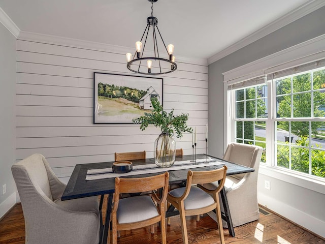 dining room with crown molding, wooden walls, wood finished floors, and a notable chandelier
