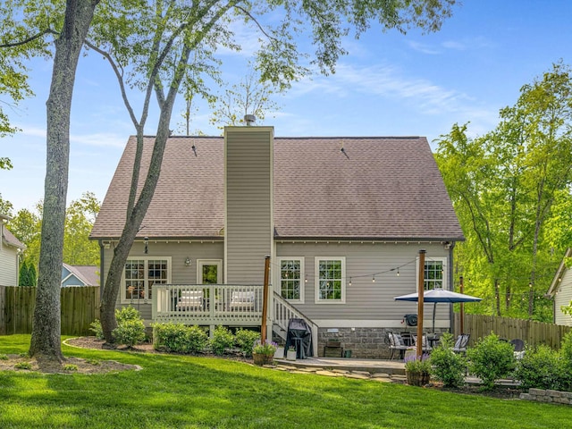 back of property featuring fence, a chimney, a yard, and a deck
