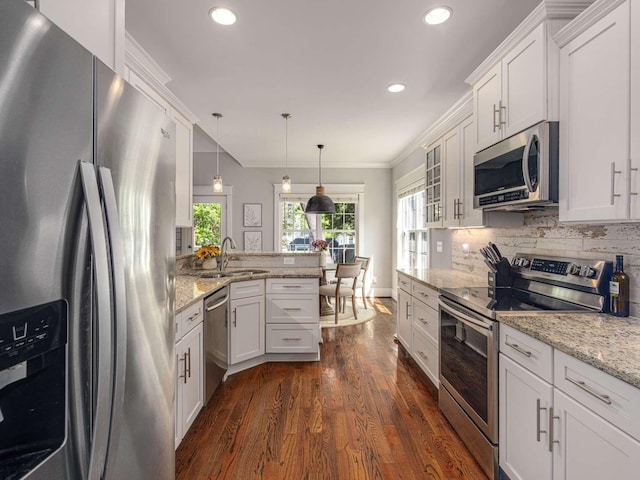 kitchen with dark wood-style flooring, a sink, a peninsula, ornamental molding, and stainless steel appliances