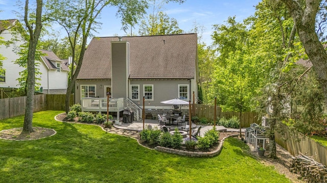 back of house featuring a wooden deck, a fenced backyard, a chimney, a patio area, and a yard