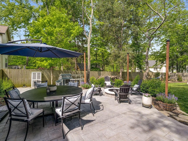 view of patio featuring a fenced backyard, outdoor dining area, and a fire pit
