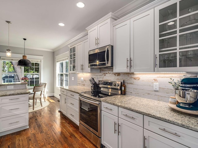 kitchen featuring crown molding, stainless steel appliances, glass insert cabinets, and tasteful backsplash
