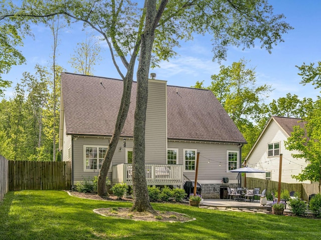 back of property featuring a wooden deck, a fenced backyard, a chimney, a patio area, and a yard