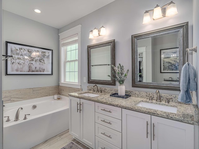 bathroom featuring a sink, double vanity, a garden tub, and wood finished floors