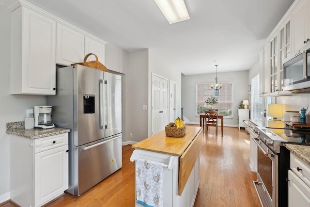104 Drayton Ct, Franklin, TN 37067 - kitchen with white cabinets, an inviting chandelier, light wood finished floors, stainless steel appliances, and glass insert cabinets