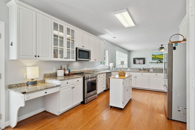 104 Drayton Ct, Franklin, TN 37067 - kitchen with glass insert cabinets, a center island, white cabinetry, light wood finished floors, and appliances with stainless steel finishes