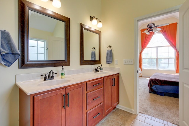 ensuite bathroom featuring double vanity, baseboards, a sink, and tile patterned floors