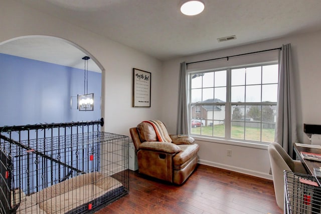 sitting room featuring visible vents, hardwood / wood-style floors, baseboards, a chandelier, and arched walkways