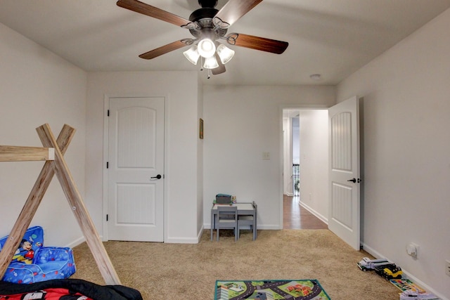 recreation room featuring baseboards, a ceiling fan, and carpet