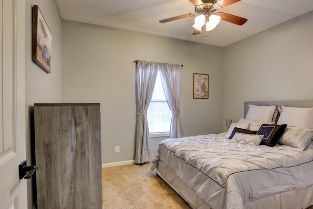 bedroom with a ceiling fan, baseboards, and light carpet