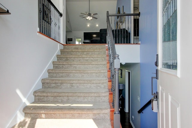 staircase featuring a high ceiling and ceiling fan