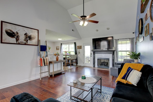 living area with high vaulted ceiling, plenty of natural light, ceiling fan, and a tile fireplace