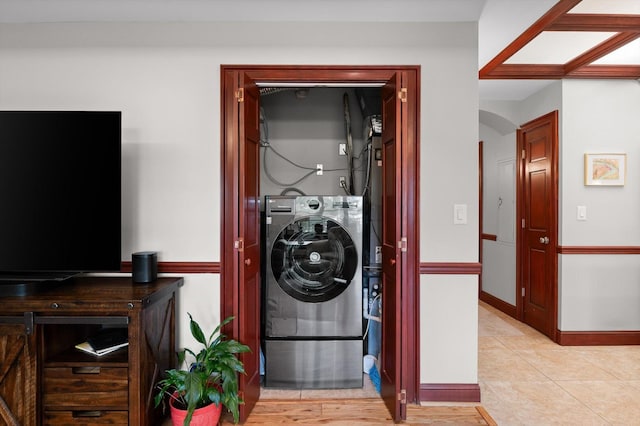 washroom featuring light tile patterned flooring, laundry area, arched walkways, baseboards, and washer / dryer