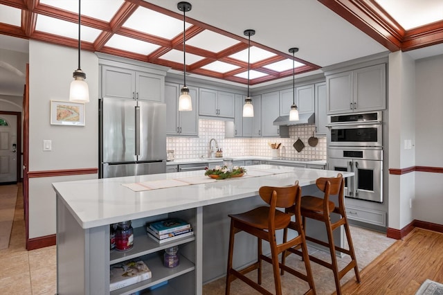 kitchen featuring stainless steel appliances, decorative backsplash, and gray cabinets