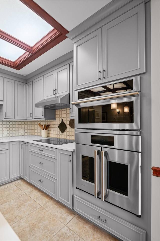 kitchen featuring light countertops, gray cabinets, black electric stovetop, and a skylight