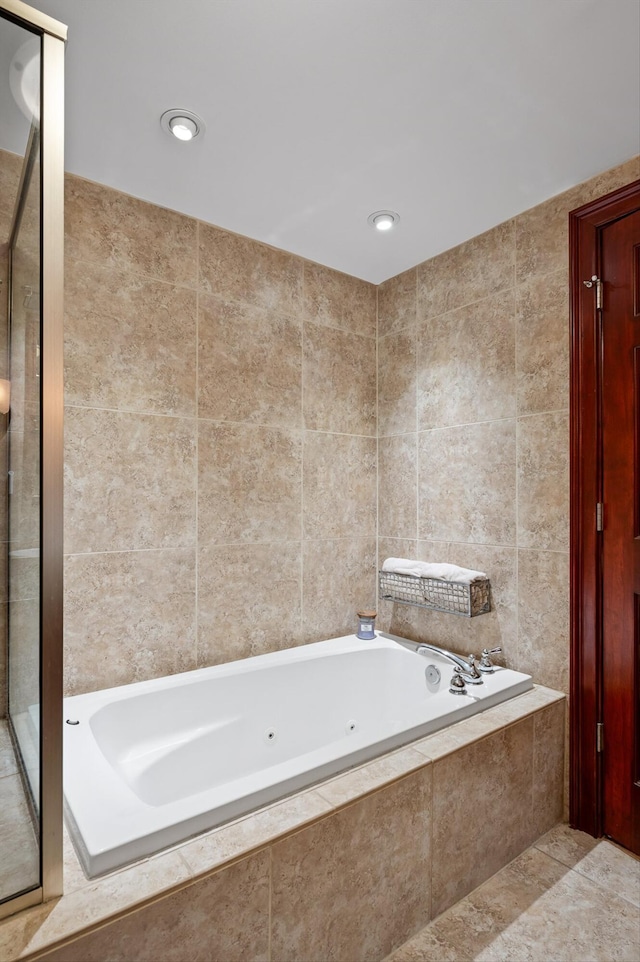 bathroom with a whirlpool tub, tile walls, and a shower stall