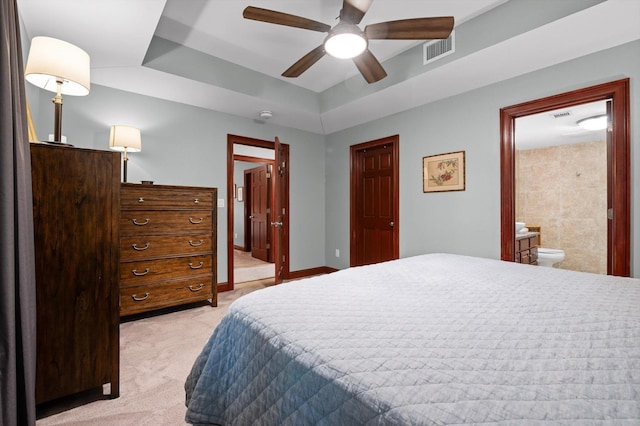 bedroom featuring visible vents, light carpet, a tray ceiling, and connected bathroom