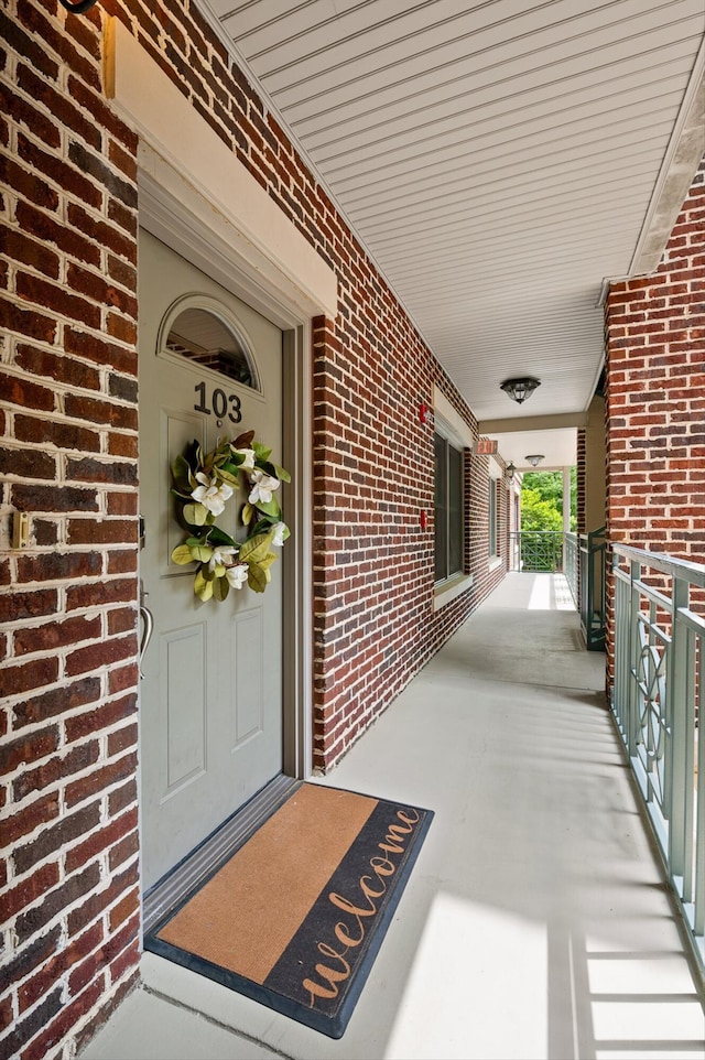 property entrance featuring covered porch and brick siding
