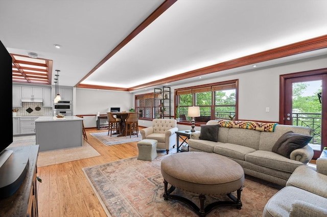 living room with recessed lighting, a raised ceiling, light wood finished floors, and a healthy amount of sunlight