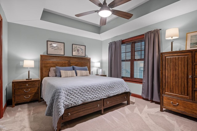 bedroom featuring baseboards, light carpet, ceiling fan, and a raised ceiling