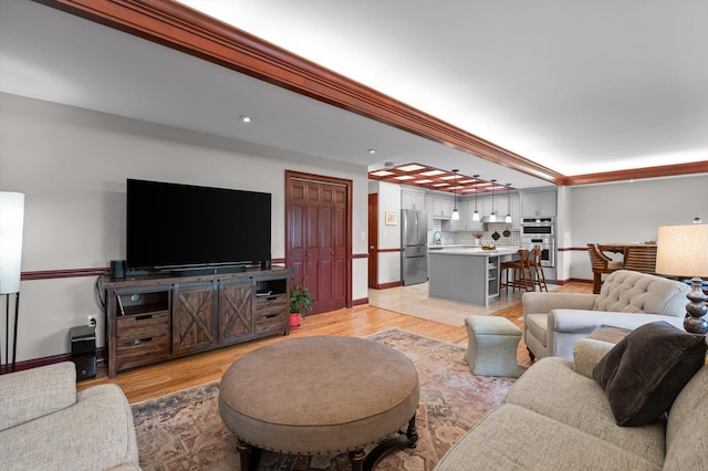 living area featuring baseboards, recessed lighting, light wood finished floors, and ornamental molding