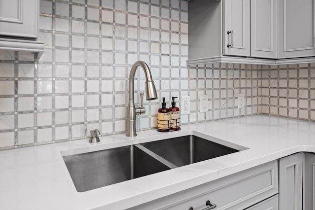 kitchen featuring a sink, decorative backsplash, and gray cabinetry