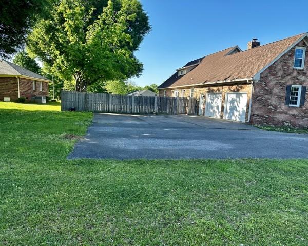 1314 Jewell Dr, Columbia, TN 38401 - view of side of home with a chimney, brick siding, fence, aphalt driveway, and a yard