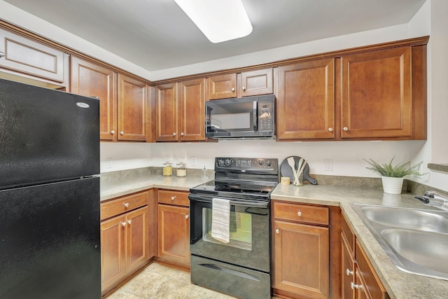 kitchen featuring a sink, light countertops, black appliances, and brown cabinets