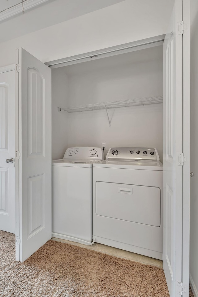 washroom featuring separate washer and dryer, laundry area, and light carpet
