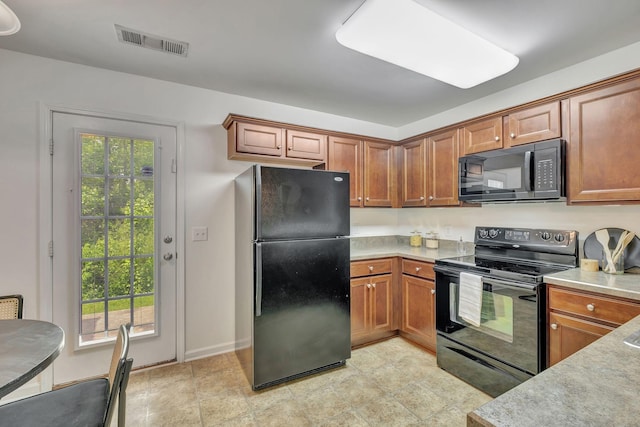 kitchen featuring visible vents, light countertops, brown cabinets, and black appliances