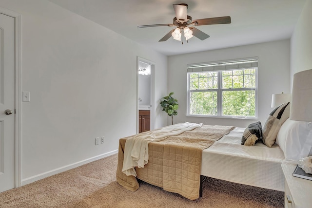 bedroom with baseboards, light colored carpet, ceiling fan, and ensuite bathroom