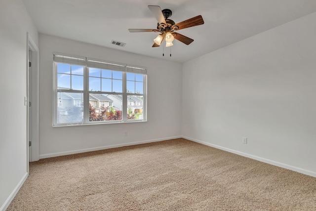 carpeted empty room with visible vents, a ceiling fan, and baseboards