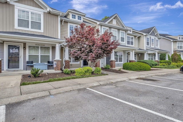 multi unit property with a porch, board and batten siding, uncovered parking, and a residential view