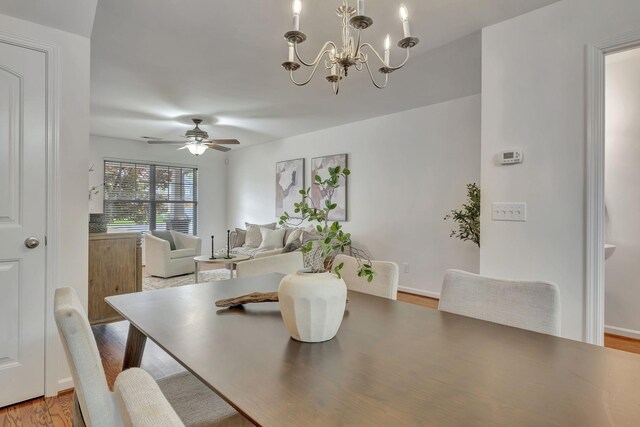 dining room with ceiling fan with notable chandelier and wood finished floors