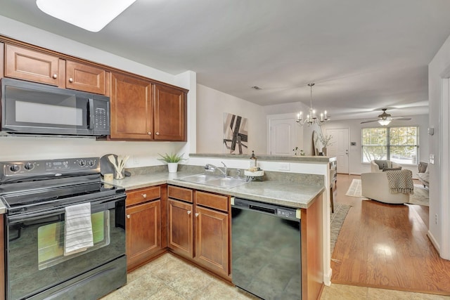 kitchen featuring a sink, light countertops, a peninsula, open floor plan, and black appliances