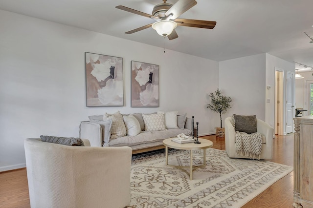 living room with baseboards, a ceiling fan, and wood finished floors