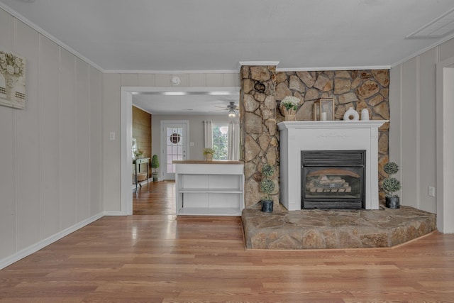 unfurnished living room featuring ornamental molding, a decorative wall, wood finished floors, and visible vents