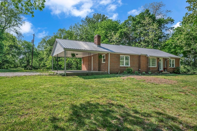 single story home featuring a chimney, metal roof, a front yard, brick siding, and an attached carport
