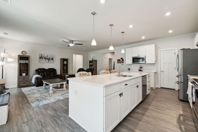907 Caywood Rd, Smyrna, TN 37167 - kitchen with wood finished floors, a sink, stainless steel appliances, open floor plan, and white cabinetry