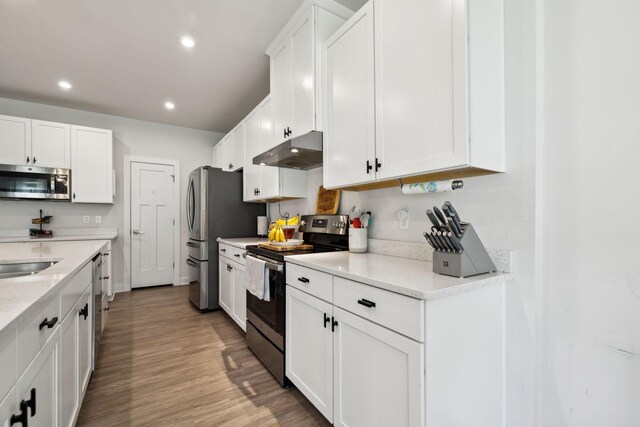 907 Caywood Rd, Smyrna, TN 37167 - kitchen with under cabinet range hood, stainless steel appliances, wood finished floors, and white cabinets